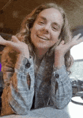 a woman wearing a plaid shirt with buttons on the sleeves is smiling