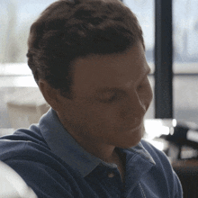 a man in a blue shirt looks down at something