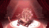 a spinning wheel with roses on it is on a stage with stairs in the background