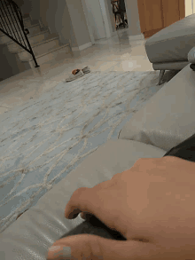 a person 's hand rests on a couch in a room