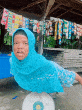 a woman wearing a blue head scarf is standing on a scale with the number 20 on it