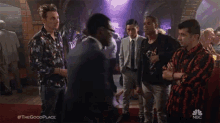 a group of men are standing in a crowded room talking to each other .