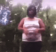 a blurry picture of a woman in a white tank top holding her belly