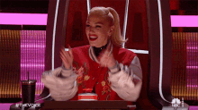 a woman in a red jacket is sitting in a chair with her arms outstretched .