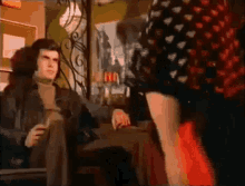 a man is sitting in a chair with a glass of wine and a woman is standing in front of him