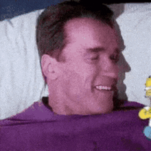 a man in a purple shirt is laying in a bed and smiling