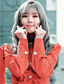a woman in a red shirt is making a heart with her hands