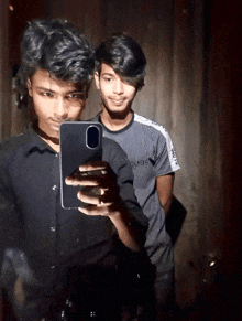 a young man taking a selfie with another young man wearing a shirt that says puma