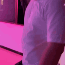 a man in a white shirt is standing in front of a purple wall