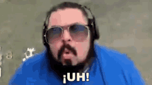 a man with a beard and sunglasses is wearing headphones and saying uh !