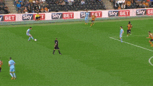 a soccer goalie dives to catch a ball in front of sky bet banners