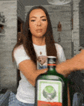 a woman holds a green bottle of jagermeister