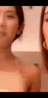 two women are standing next to each other in a room and one of them is wearing a white tank top