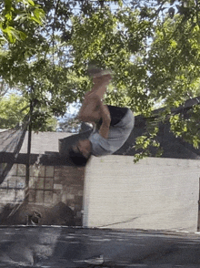 a man is doing a flip on a trampoline in front of a house .
