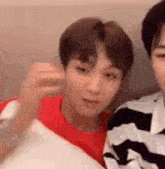 two young men are sitting next to each other on a couch and one of them is holding a pillow .