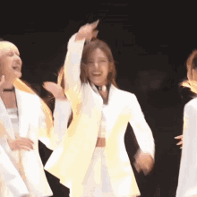 a woman in a white suit is dancing with her hands in the air