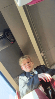a boy in a suit and tie is sitting in a bus