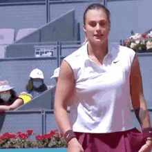 a woman is standing on a tennis court wearing a white shirt and purple skirt .
