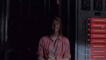 a woman in a pink shirt stands in front of a row of red buttons that say " emergency exit "
