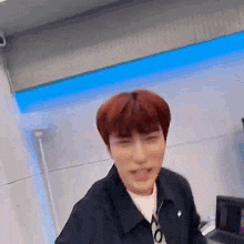 a man with red hair is standing in a room with a blue wall .