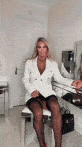 a woman in a white jacket is sitting on a chair in front of a mirror
