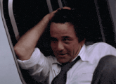 a man in a white shirt and tie is looking out the window