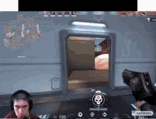 a man wearing headphones holds a gun in front of a screen that says kapwing at the bottom