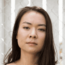 a woman with long brown hair looks at the camera