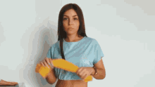 a woman in a blue crop top is dancing with a yellow towel in her hand .