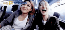 two women are sitting on a plane and laughing .
