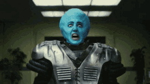 a man with a blue face and a metallic jacket is making a funny face