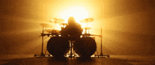 a person playing a drum set in front of a bright sun