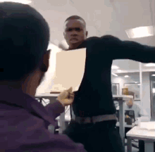 a man in a black shirt is holding a piece of paper in his hand .