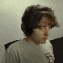 a young man wearing headphones and a t-shirt is sitting in a chair .