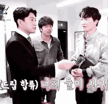 a man in a suit shakes hands with another man in a room with chinese writing on the wall