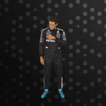 a man in a petronas racing suit is standing in front of a black background