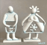 a statue of a man holding a watering can next to a statue of a woman