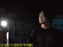 a man holding a bottle of water in a dark room with korean writing on the bottom