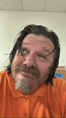 a man with a beard and long hair is wearing an orange shirt