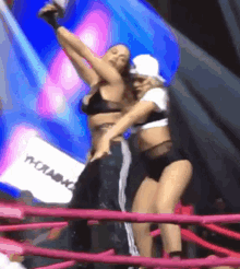 two women are dancing in a ring with a sign that says moramo on it