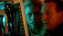 a man and a woman in a dark room looking at something