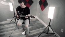 a man is playing a guitar in a room