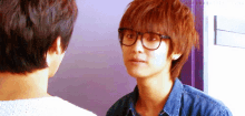 a man wearing glasses looks at another man 's face