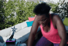 a woman in a pink tank top sits on a couch next to a star trophy