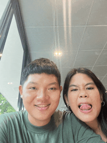 a man and a woman are posing for a picture and one of them is sticking her tongue out