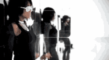 a woman wearing sunglasses standing in front of a mirror