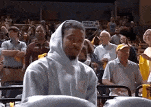 a man wearing a hooded sweatshirt is sitting in a stadium with a sign that says focus ! execute !