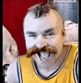 a man with a mohawk and a mustache wearing a yellow jersey