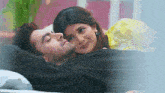 a man and a woman are laying on a bed and the woman is looking at the man 's face .
