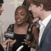 a woman in a black dress is being interviewed by a man with a hollywood microphone